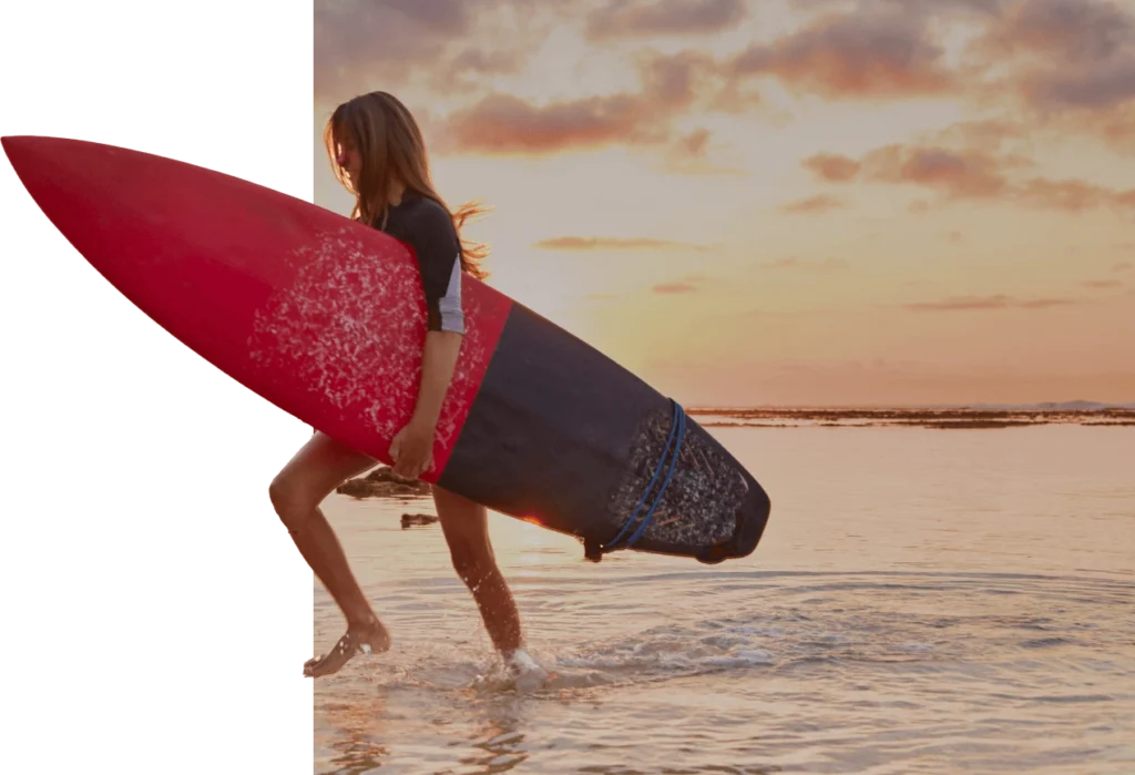 Surfer walking along Hiriketiya Beach at sunset near best hotels Hiriketiya Sri Lanka