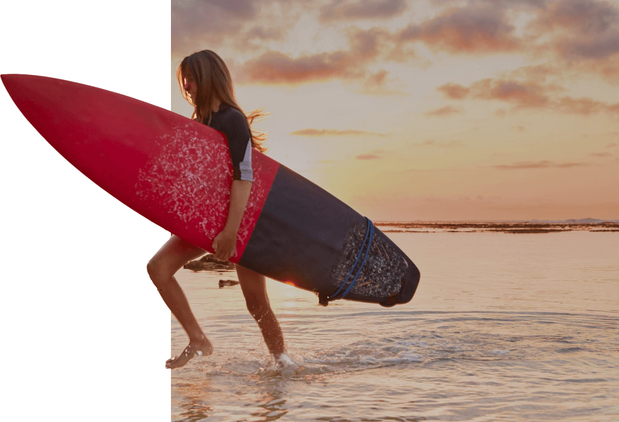 Surfer walking along Hiriketiya Beach at sunset near best hotels Hiriketiya Sri Lanka