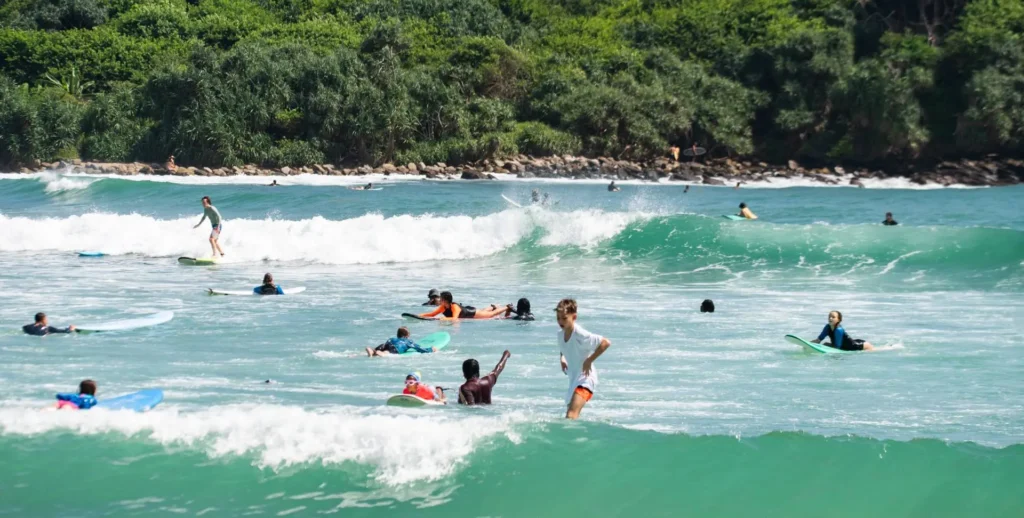 Surfing and swimming at Hiriketiya Bay Sri Lanka with turquoise waves and tropical beach