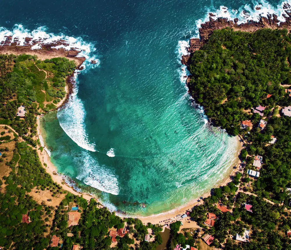 Aerial view of Hiriketiya Bay with turquoise water and Hiriketiya beach hotels along the coastline in Sri Lanka